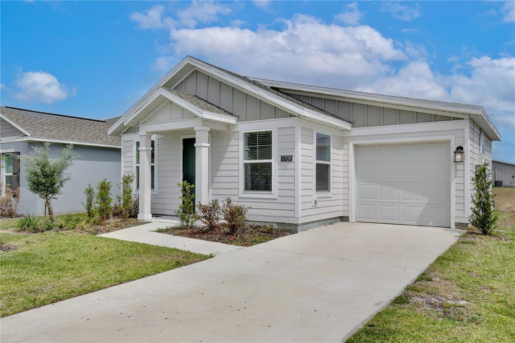 A single-story house with white horizontal siding, a front porch, and an attached garage — 1709 TEAGAN LANE, WINTER HAVEN, FL
