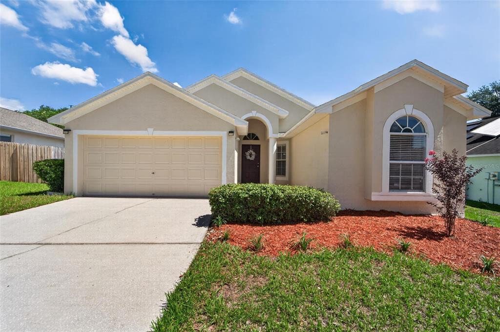 A single-story house with a beige stucco exterior, a two-car garage, and a front lawn — 418 HENDERSON AVENUE, SEFFNER, FL