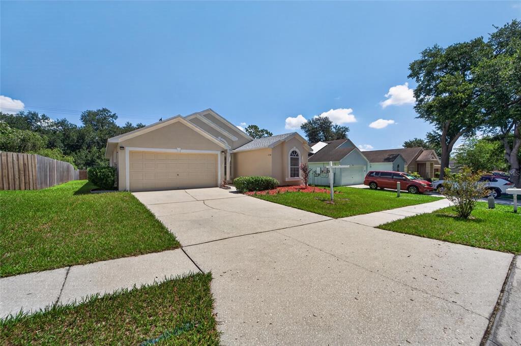 A single-story house with a beige exterior, a two-car garage, and a concrete driveway — 418 HENDERSON AVENUE, SEFFNER, FL