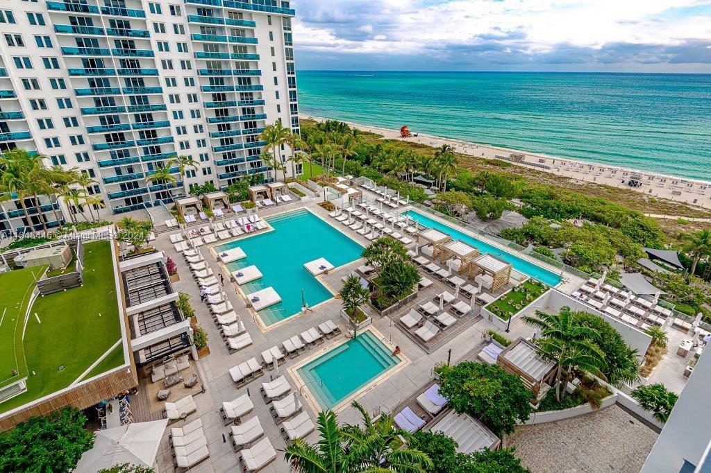 An aerial view of a hotel pool deck with lounge chairs and the ocean beyond — 2301 Collins Ave # 1115, Miami Beach FL 33139, MIAMI BEACH, FL