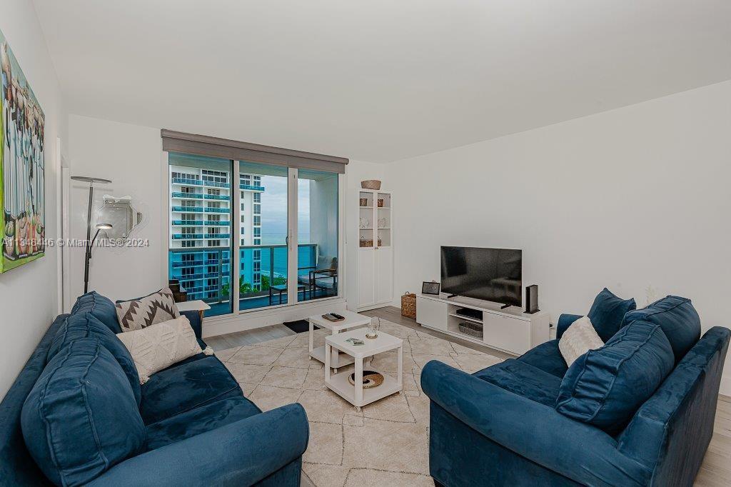 A living room features two blue sofas, a white coffee table, and a balcony view — 2301 Collins Ave # 1115, Miami Beach FL 33139, MIAMI BEACH, FL