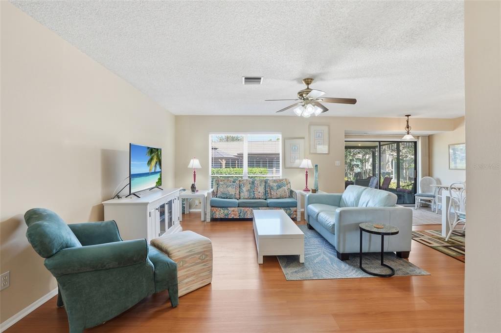 A living room features light wood floors, a blue sofa, and a floral patterned sofa — 4289 ISLAND CIRCLE UNIT 1, FORT MYERS, FL