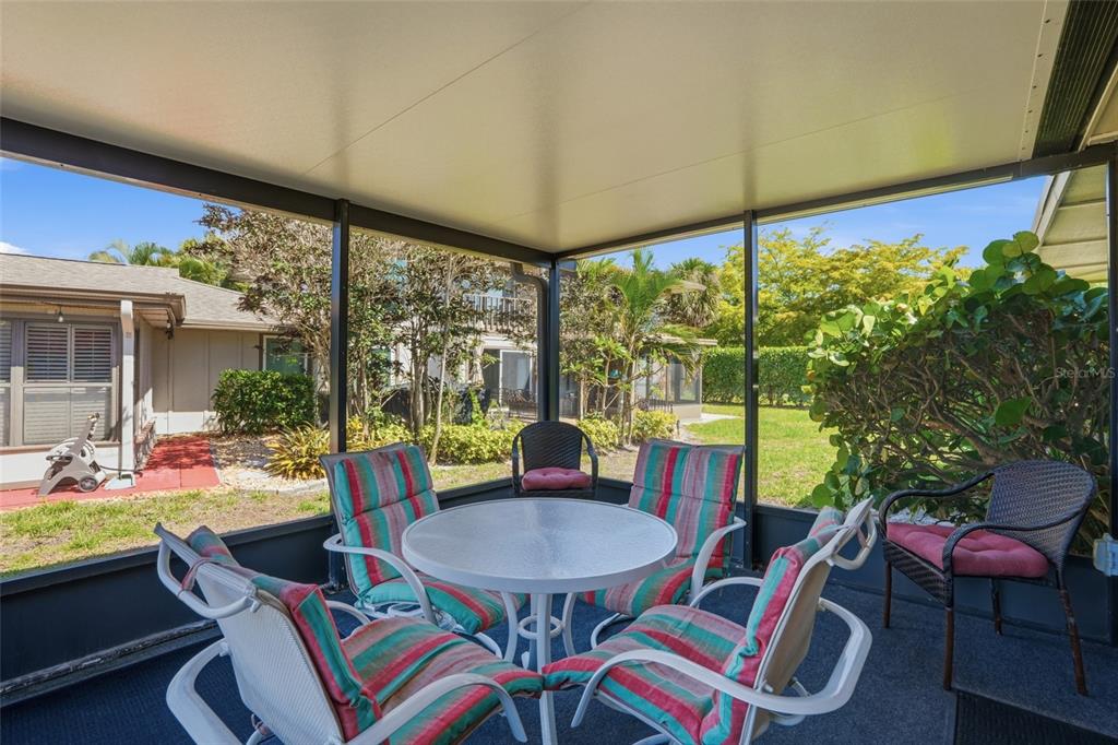 A screened-in patio features a round glass table with four striped chairs and outdoor views — 4289 ISLAND CIRCLE UNIT 1, FORT MYERS, FL