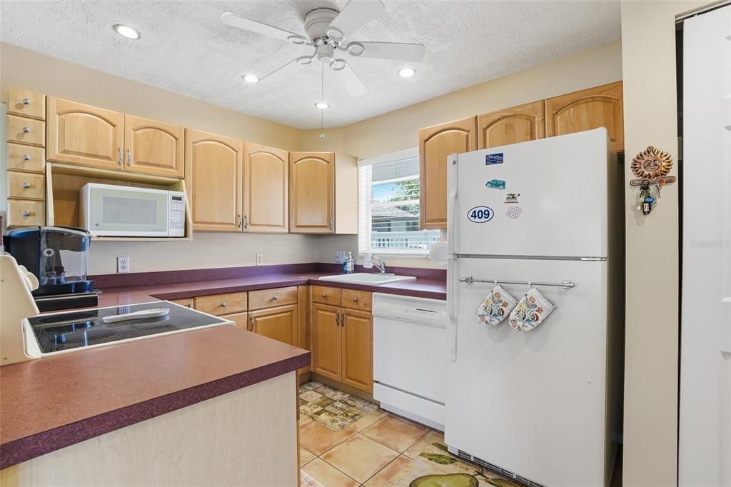 A kitchen features light wood cabinets, a white refrigerator, and a dark countertop — 4289 ISLAND CIRCLE UNIT 1, FORT MYERS, FL