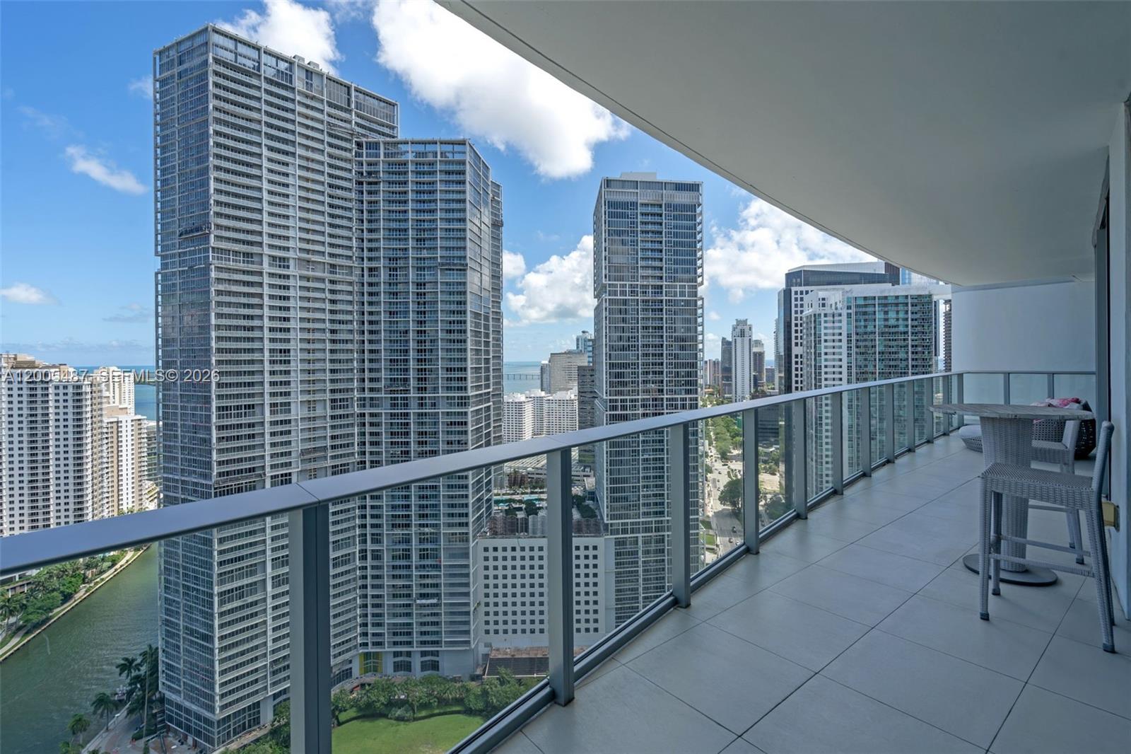 A high-rise balcony with a glass railing overlooks a dense city skyline and water — 200 Biscayne Boulevard Way # 3407, Miami FL 33131, MIAMI, FL