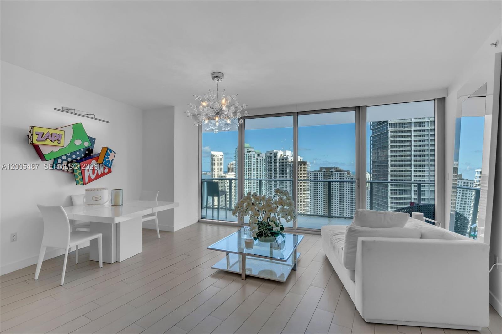 A modern living and dining area with white furniture, a glass coffee table, and city views — 200 Biscayne Boulevard Way # 3407, Miami FL 33131, MIAMI, FL