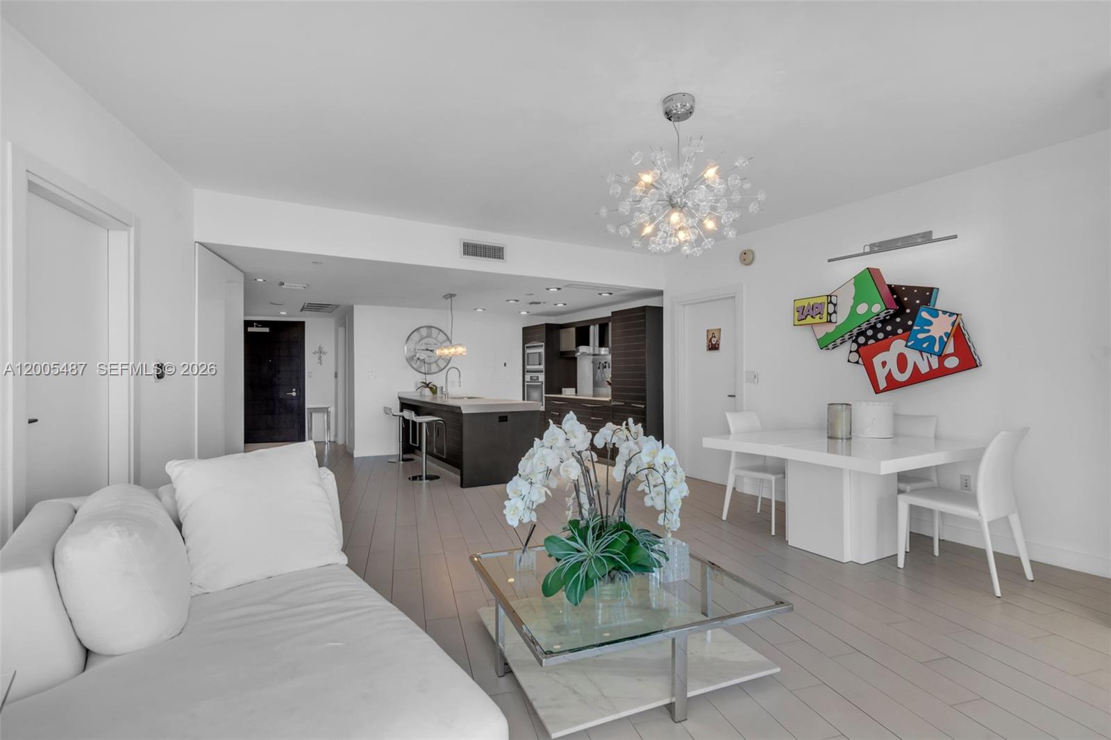 This open-concept living and dining area features white walls, light wood flooring, and modern furniture — 200 Biscayne Boulevard Way # 3407, Miami FL 33131, MIAMI, FL