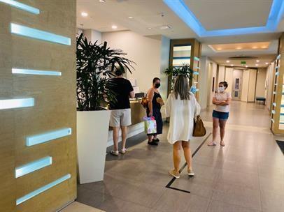 People stand at a reception desk in a modern, well-lit building lobby — 1900 N Bayshore Drive # 1705, Miami FL 33132, MIAMI, FL