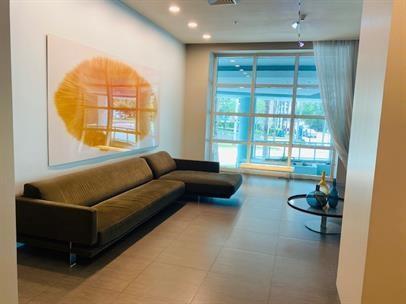 A modern lounge area features a large sectional sofa, abstract wall art, and floor-to-ceiling windows — 1900 N Bayshore Drive # 1705, Miami FL 33132, MIAMI, FL