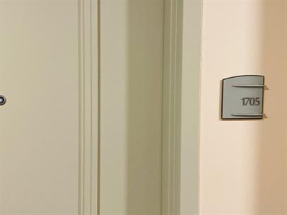 A closed door with a peephole is next to a wall sign labeled 1705 — 1900 N Bayshore Drive # 1705, Miami FL 33132, MIAMI, FL