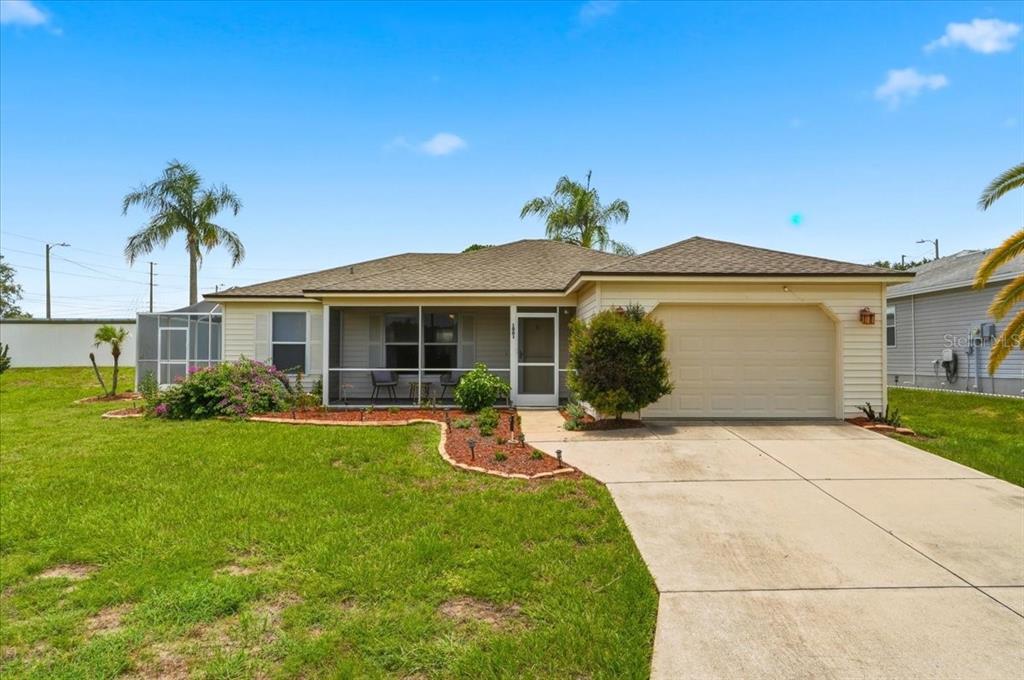 A single-story house with a screened front porch, a garage, and a landscaped front yard — 1001 CANARY CIRCLE S, LAKELAND, FL