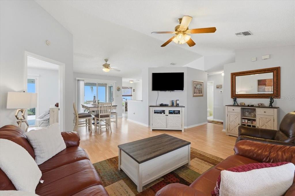 A living room with leather sofas, a coffee table, and a dining area beyond — 1001 CANARY CIRCLE S, LAKELAND, FL