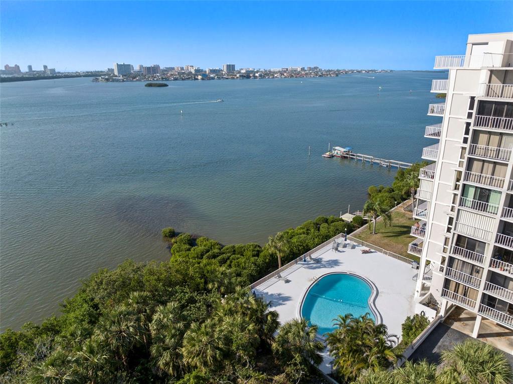 An aerial view shows a swimming pool next to a high-rise building and water — 500 N OSCEOLA AVENUE UNIT 406, CLEARWATER, FL