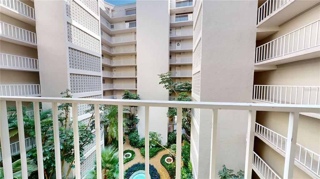 A view from a balcony overlooking a multi-story apartment building's central courtyard and garden — 500 N OSCEOLA AVENUE UNIT 406, CLEARWATER, FL