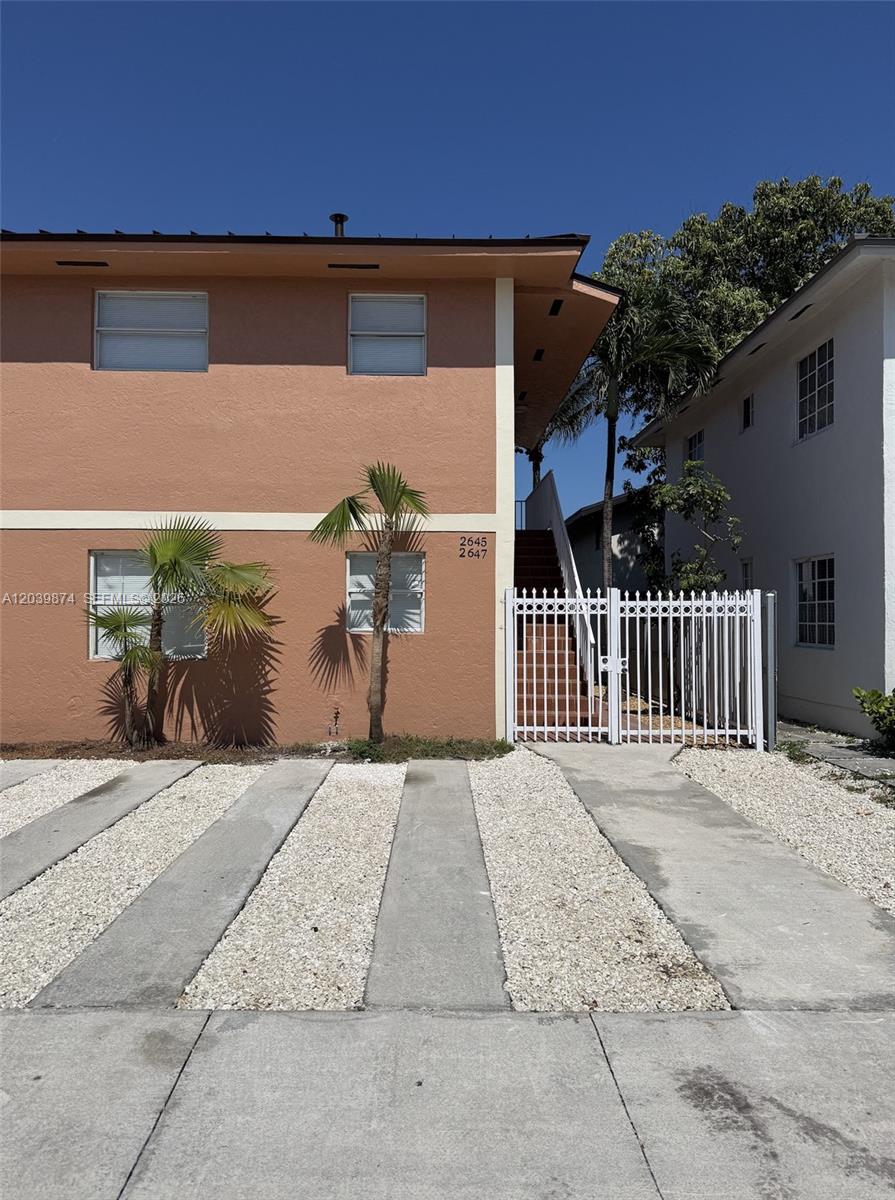 A two-story peach-colored apartment building features a white gate and a gravel driveway — 2645 SW 28th Ct # 2645, Miami FL 33133, MIAMI, FL