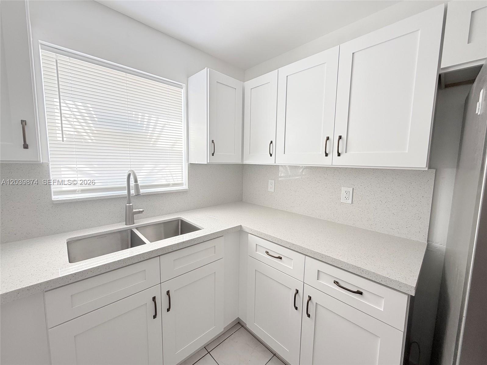 A kitchen features white shaker cabinets, speckled quartz countertops, and a stainless steel double sink — 2645 SW 28th Ct # 2645, Miami FL 33133, MIAMI, FL
