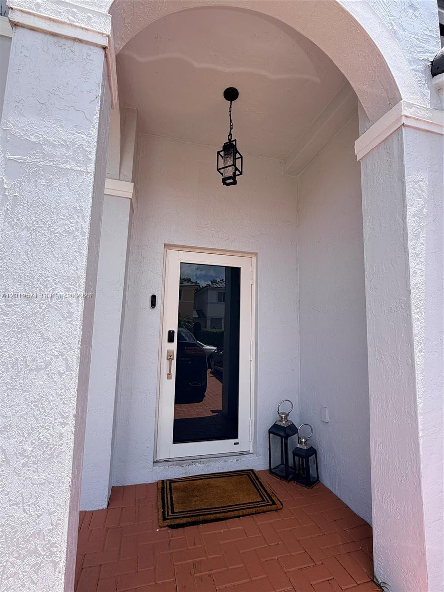 A covered entryway features a white door, a hanging lantern, and a brick floor — 13361 SW 143rd Ter # 0, Miami FL 33186, MIAMI, FL