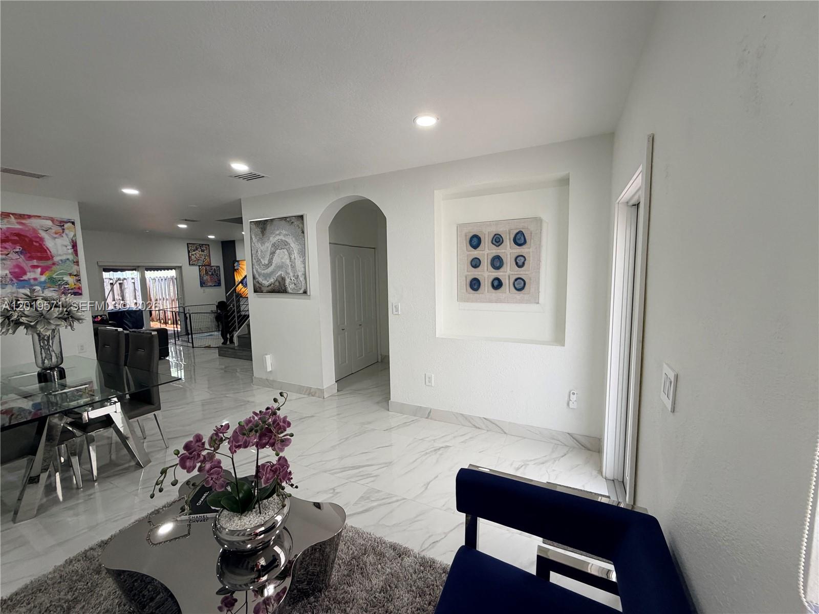 A bright dining and living area features white marble flooring, recessed wall art, and modern furniture — 13361 SW 143rd Ter # 0, Miami FL 33186, MIAMI, FL