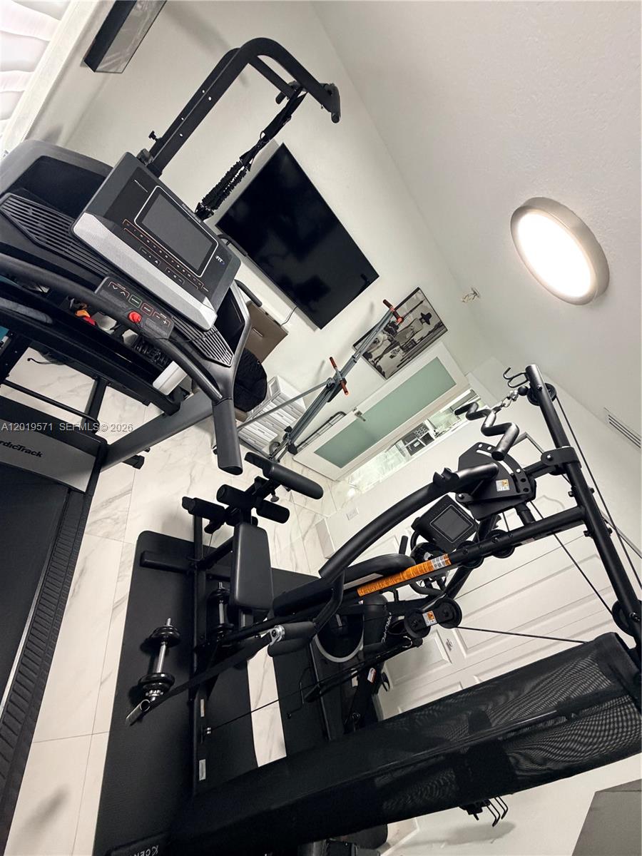 A home gym features a treadmill, a multi-station weight machine, and a wall-mounted television — 13361 SW 143rd Ter # 0, Miami FL 33186, MIAMI, FL