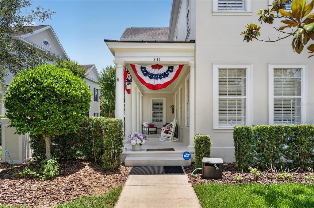 A front porch with white columns, a patriotic bunting, and a rocking chair — 331 CELEBRATION BOULEVARD, CELEBRATION, FL