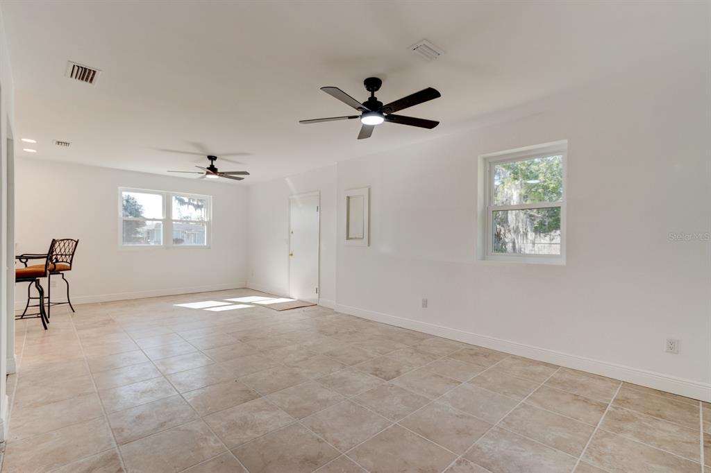 An empty room with white walls, tile flooring, two ceiling fans, and two windows — 4 MAIN STREET, PORT ORANGE, FL