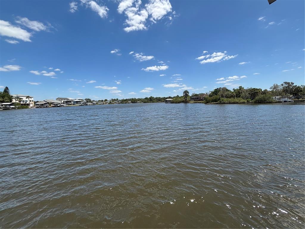 A view of a wide, rippling canal lined with houses and trees under a blue sky — 9922 ALAVISTA DRIVE, GIBSONTON, FL
