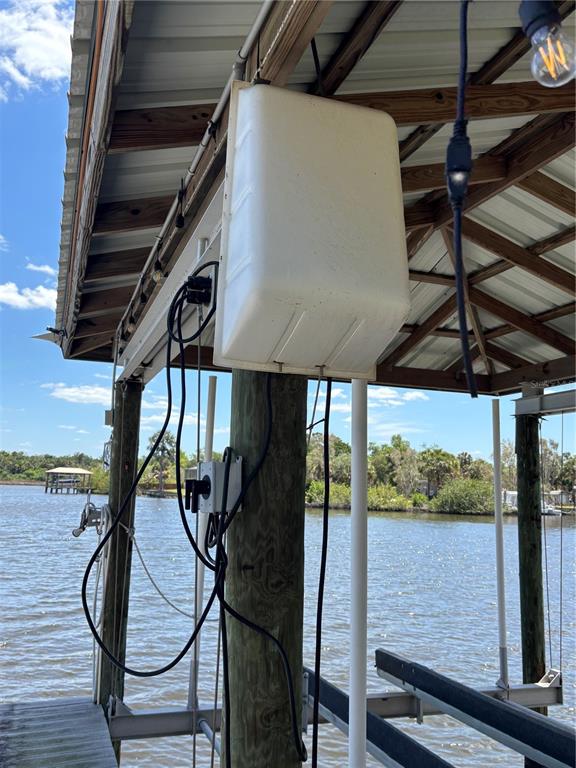 A boat lift motor cover is mounted to a wooden piling under a dock roof — 9922 ALAVISTA DRIVE, GIBSONTON, FL