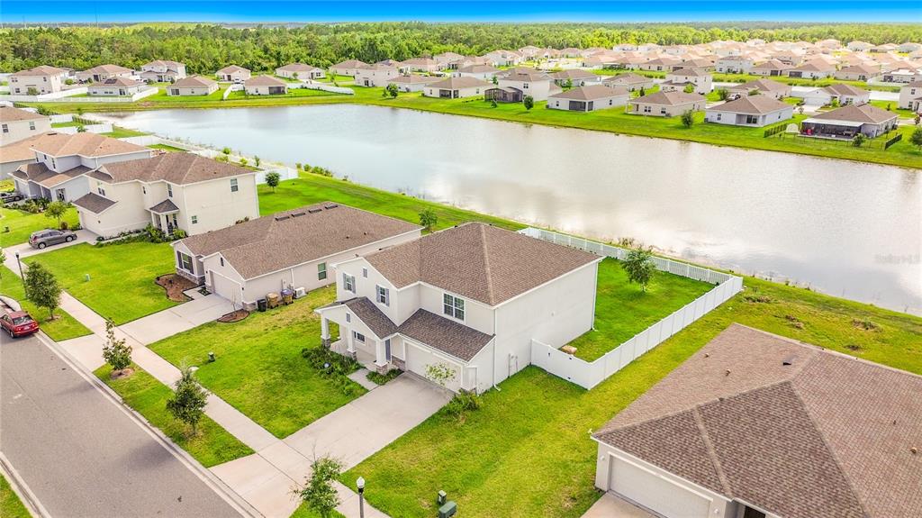 An aerial view shows a two-story house with a fenced backyard and a nearby pond — 246 ZIRCON ROAD, KISSIMMEE, FL