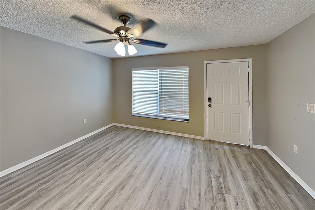An empty room features light gray walls, wood-look vinyl flooring, a ceiling fan, and blinds — 3352 MERCHANT TERRACE, DELTONA, FL
