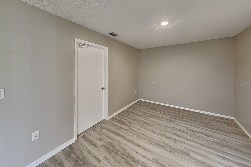 An empty room features gray walls, light wood-look flooring, and a single white door — 3352 MERCHANT TERRACE, DELTONA, FL