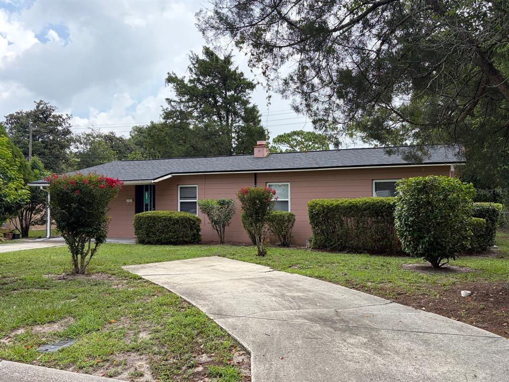 A single-story house with tan siding, a dark roof, and a concrete driveway — 901 NE 23RD STREET, GAINESVILLE, FL