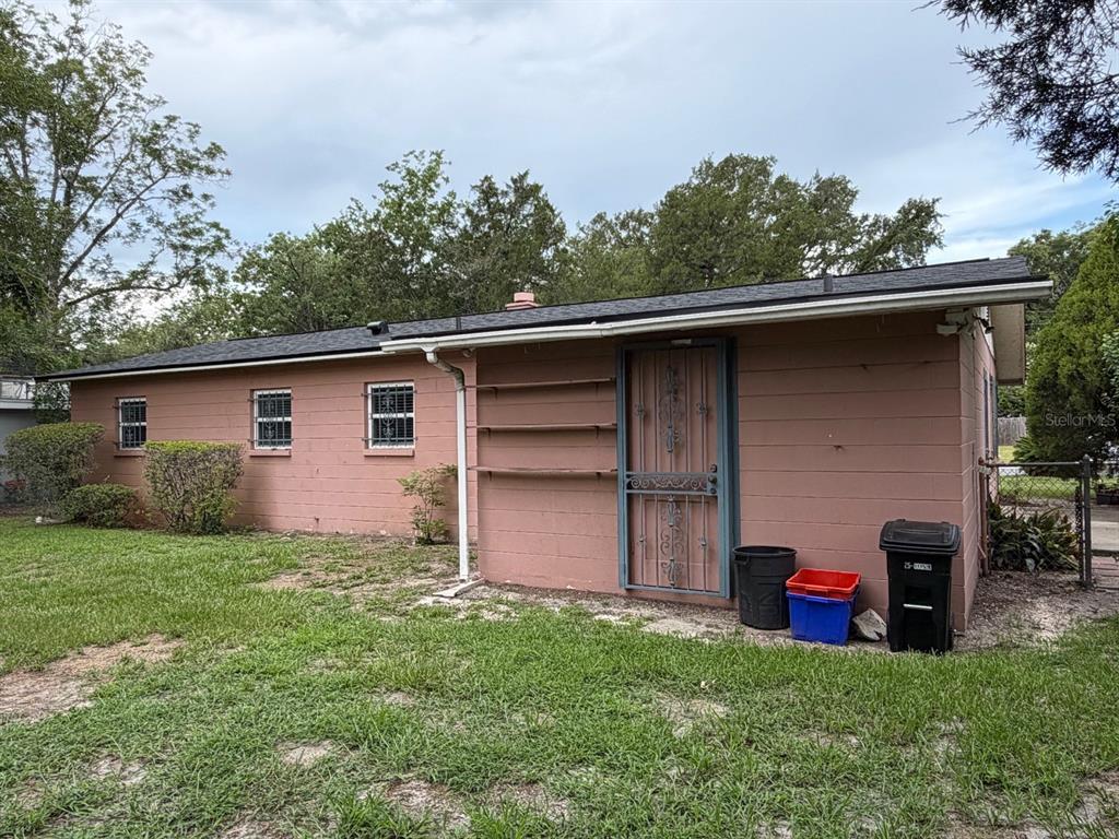 A pink concrete block house exterior features a metal security door and three small windows — 901 NE 23RD STREET, GAINESVILLE, FL