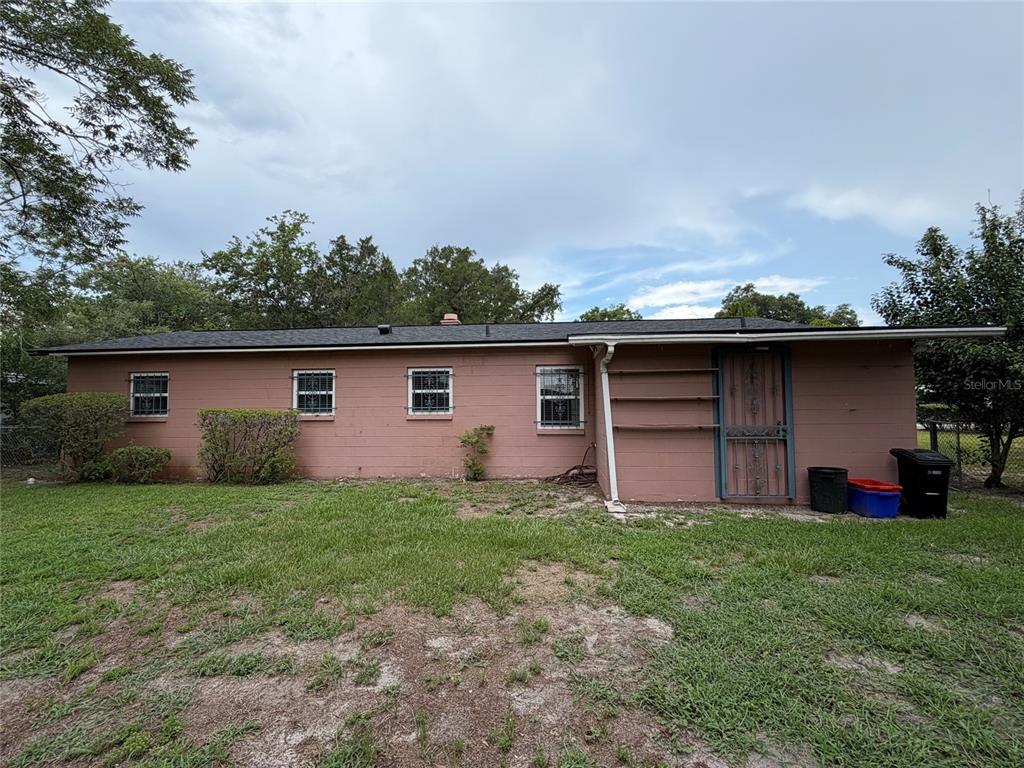 The exterior of a single-story house with pink siding, four windows, and a metal door — 901 NE 23RD STREET, GAINESVILLE, FL