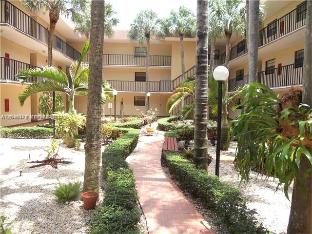 A courtyard features a brick walkway, palm trees, and gravel landscaping between apartment building wings — 10845 SW 112th Ave # 211, Miami FL 33176, MIAMI, FL