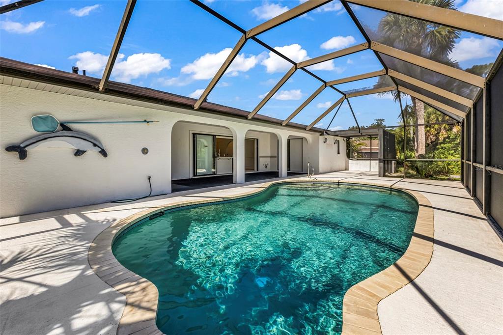A screened-in swimming pool with a tan paver border sits on a concrete patio — 18250 GRACE AVENUE, PORT CHARLOTTE, FL