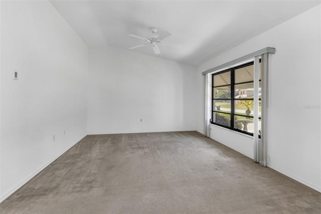 An empty room with white walls, beige carpet, a ceiling fan, and a large window — 18250 GRACE AVENUE, PORT CHARLOTTE, FL