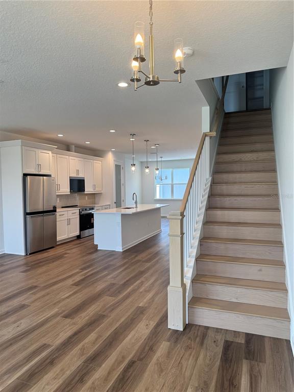 A kitchen with white cabinets and an island sits beside a wooden staircase — 1888 CROWNCREST DRIVE, APOPKA, FL