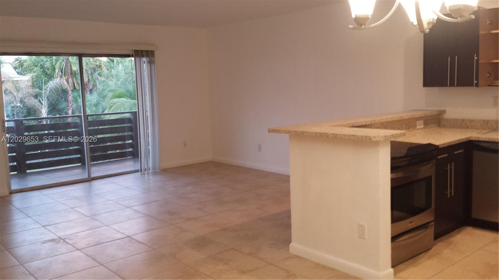 A kitchen with dark cabinets and granite countertops opens to a tiled living area — 7473 SW 82nd St # A313, Miami FL 33143, MIAMI, FL