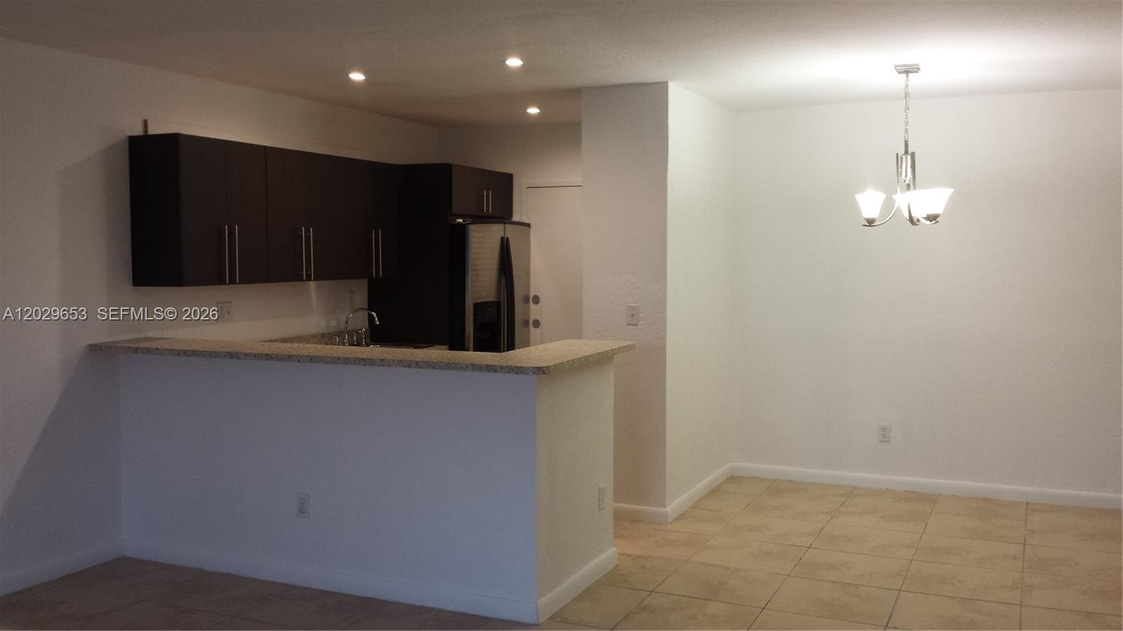 A kitchen with dark cabinets and a breakfast bar overlooks a dining area — 7473 SW 82nd St # A313, Miami FL 33143, MIAMI, FL
