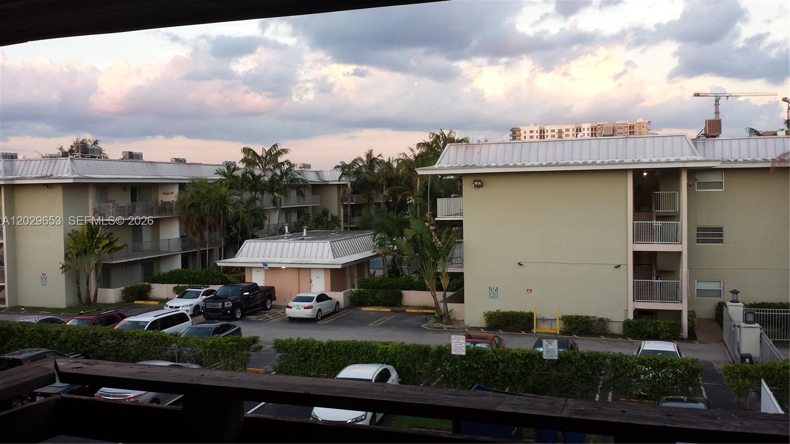 An exterior view shows apartment buildings, a parking lot with several cars, and palm trees — 7473 SW 82nd St # A313, Miami FL 33143, MIAMI, FL