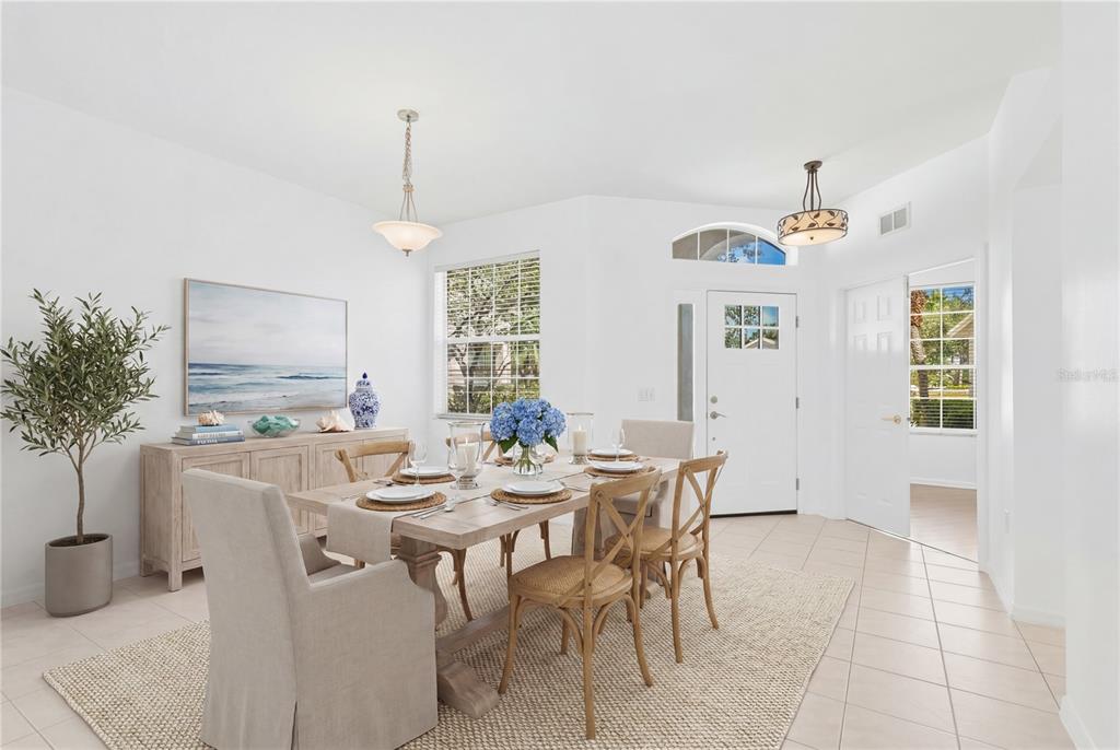 A dining room features a wooden table, upholstered chairs, a sideboard, and tile flooring — 14243 CATTLE EGRET PLACE, BRADENTON, FL