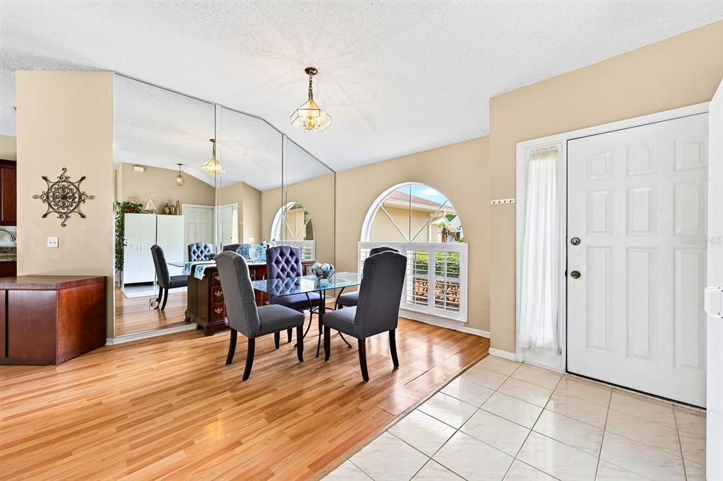 A dining area features a mirrored wall, wood flooring, and a glass-topped table with chairs — 259 SILK BAY PLACE, LONGWOOD, FL