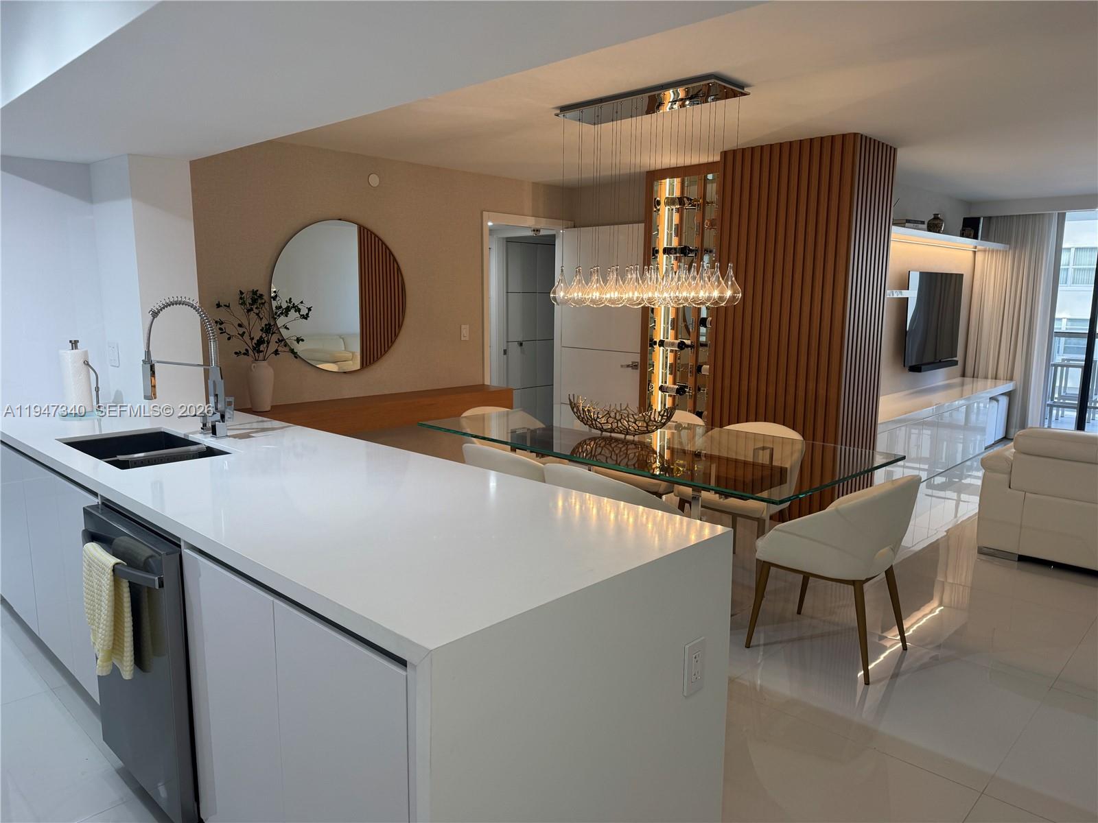 A modern kitchen and dining area feature white countertops, a glass table, and wood paneling — 5757 Collins Ave # 504, Miami Beach FL 33140, MIAMI BEACH, FL