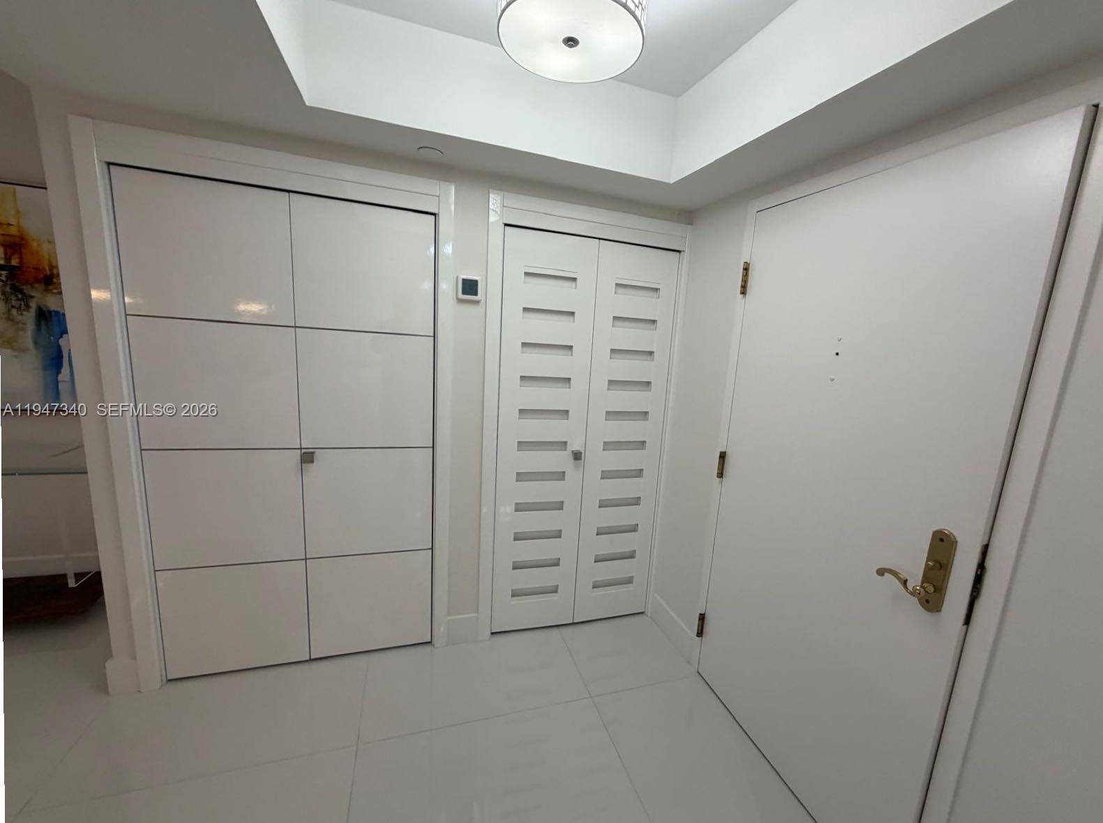 An entryway features white tile flooring, two sets of closet doors, and a main door — 5757 Collins Ave # 504, Miami Beach FL 33140, MIAMI BEACH, FL