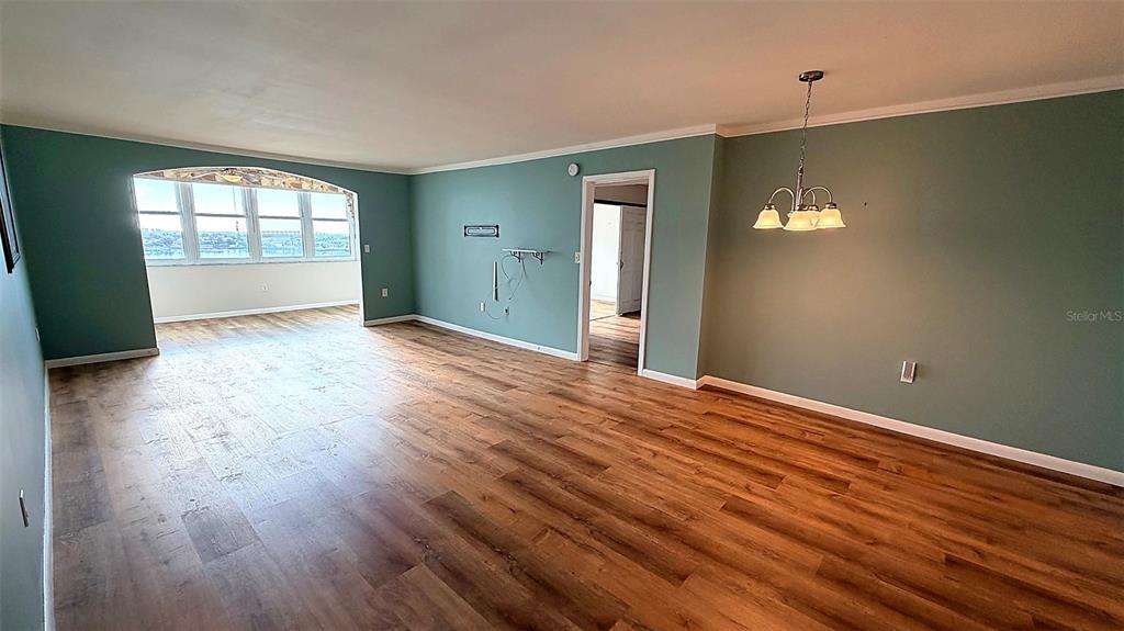 An open-concept living and dining area features light green walls and wood-look flooring — 5130 BRITTANY DRIVE S UNIT 807, ST PETERSBURG, FL