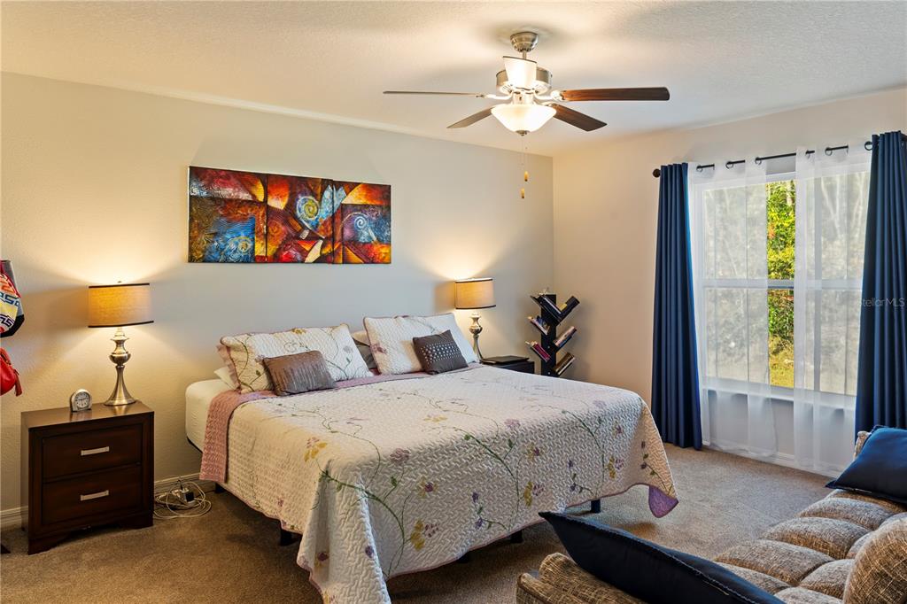 A bedroom features a king-sized bed, a ceiling fan, two nightstands, and a large window — 369 MARION OAKS MANOR, OCALA, FL