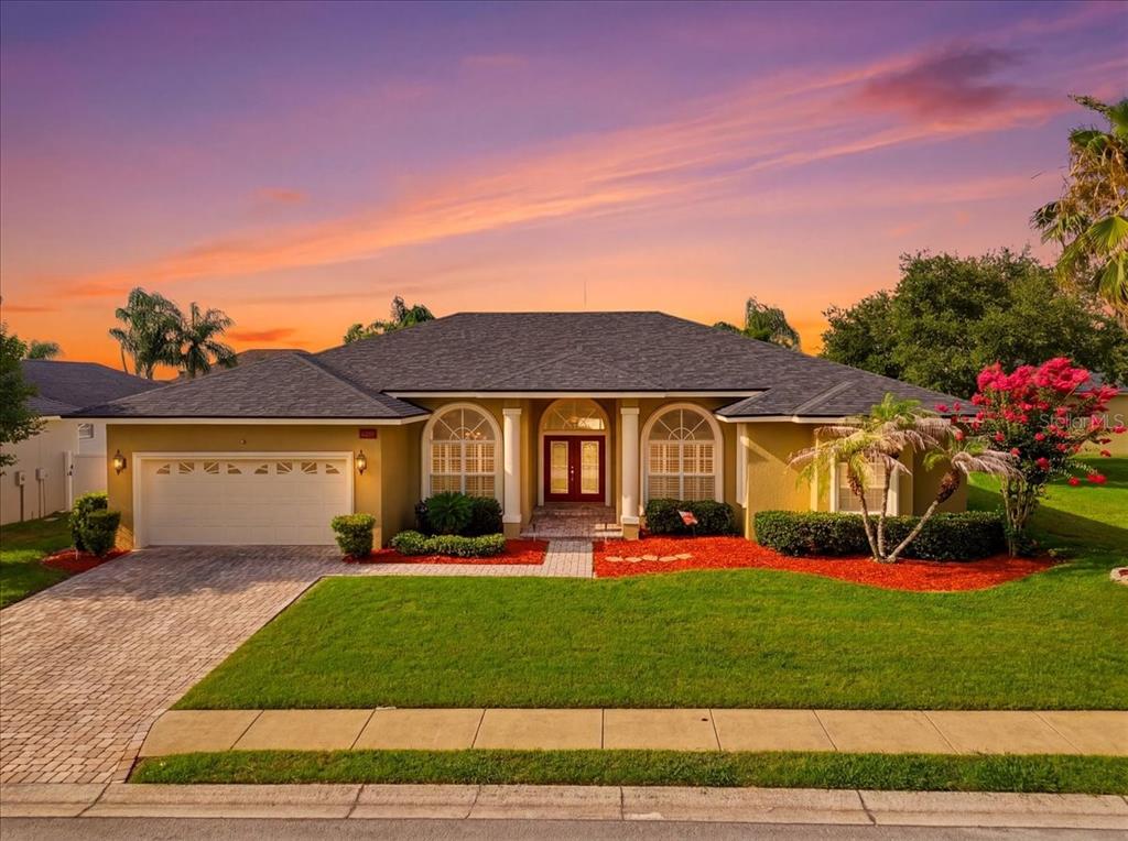 A single-story house with a two-car garage, arched windows, and a paved driveway at sunset — 2280 CHESTERFIELD CIRCLE, LAKELAND, FL