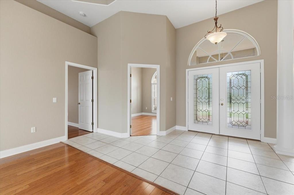An entryway features light-colored floor tiles, hardwood flooring, double front doors, and high ceilings — 2280 CHESTERFIELD CIRCLE, LAKELAND, FL