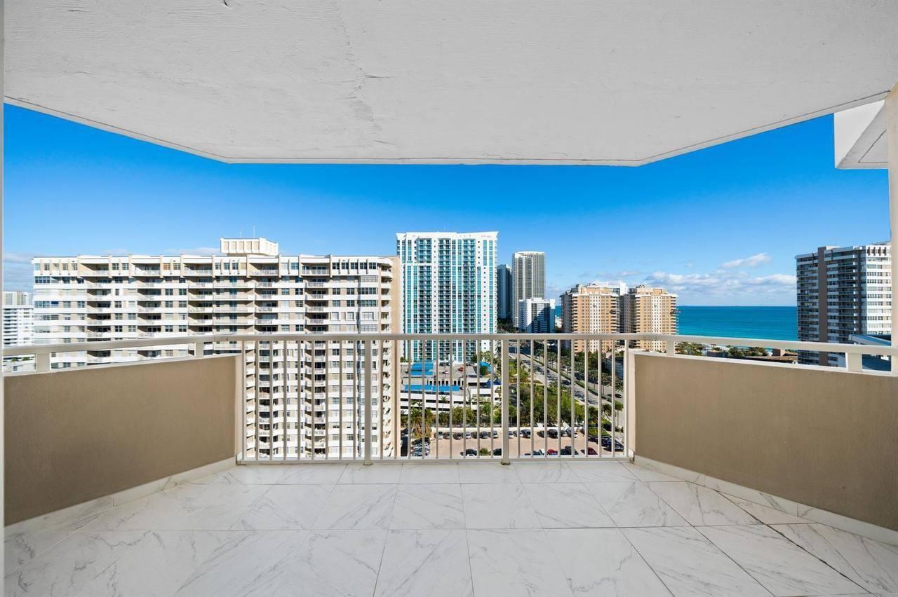 A balcony with white marble-look tile flooring overlooks a city skyline and the ocean — 1985 S Ocean Drive # 16b, Hallandale Beach FL 33009, HALLANDALE BEACH, FL