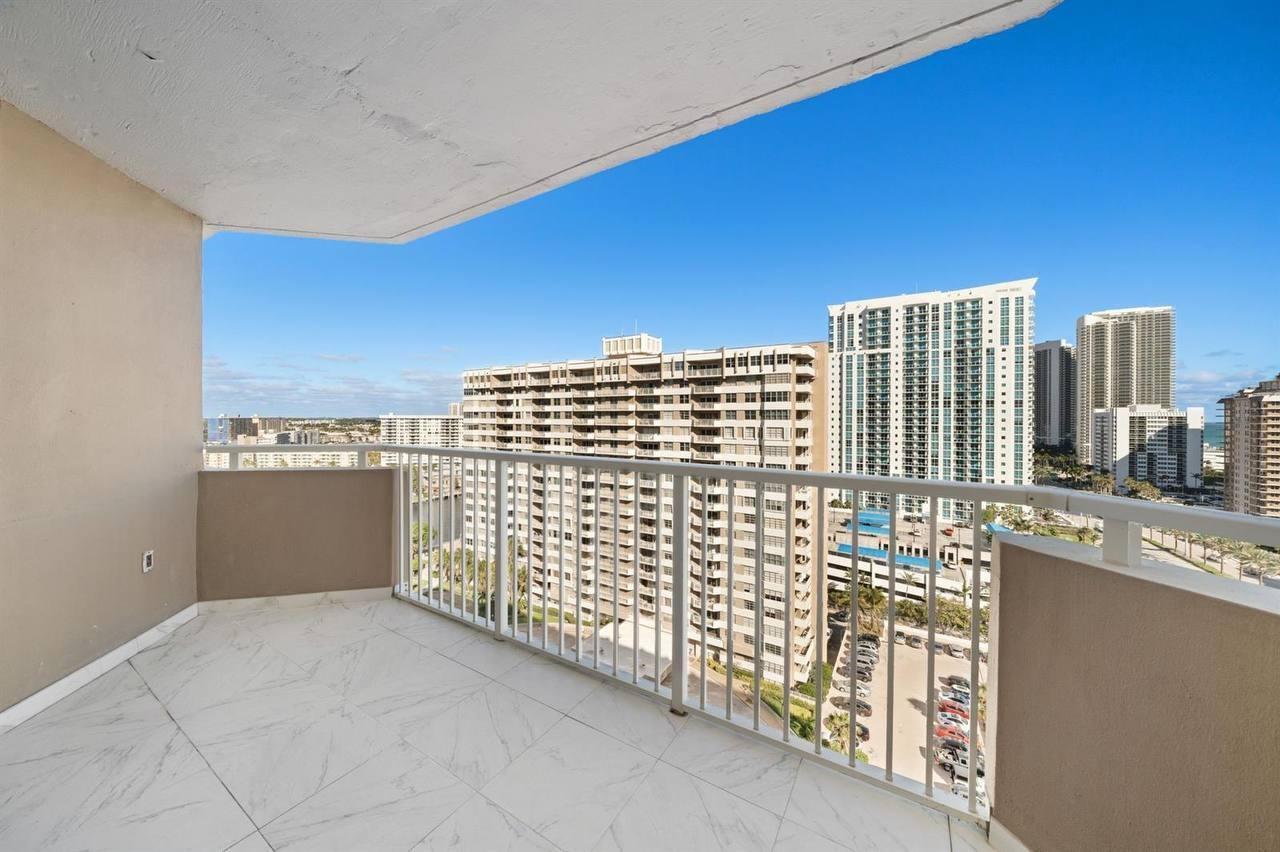 A balcony with white marble-look tile flooring overlooks a city skyline and nearby high-rise buildings — 1985 S Ocean Drive # 16b, Hallandale Beach FL 33009, HALLANDALE BEACH, FL